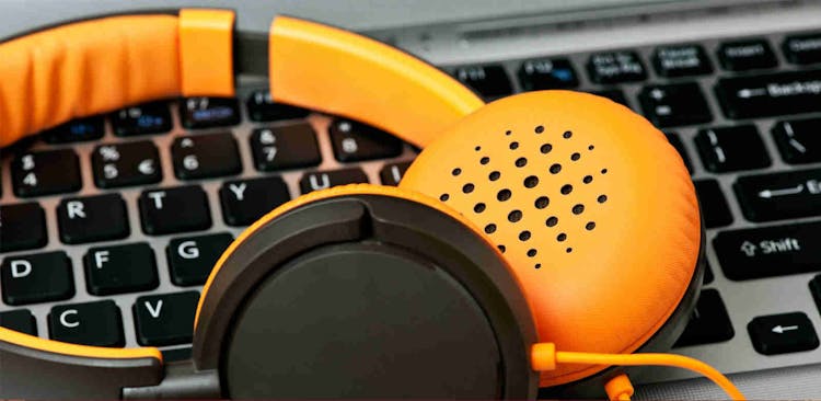 A pair of orange headphones resting on a laptop keyboard